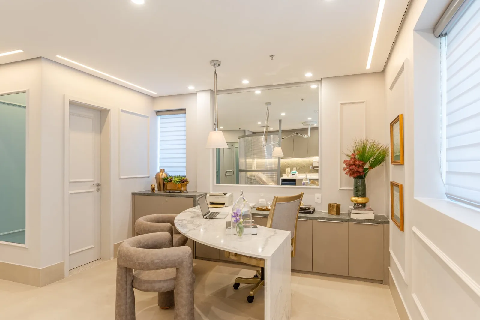 Sala de atendimento com mesa curva de mármore e poltronas confortáveis